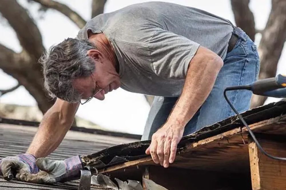 A man on a roof with a tool, showcasing our professional roof installation services in Spokane, WA.