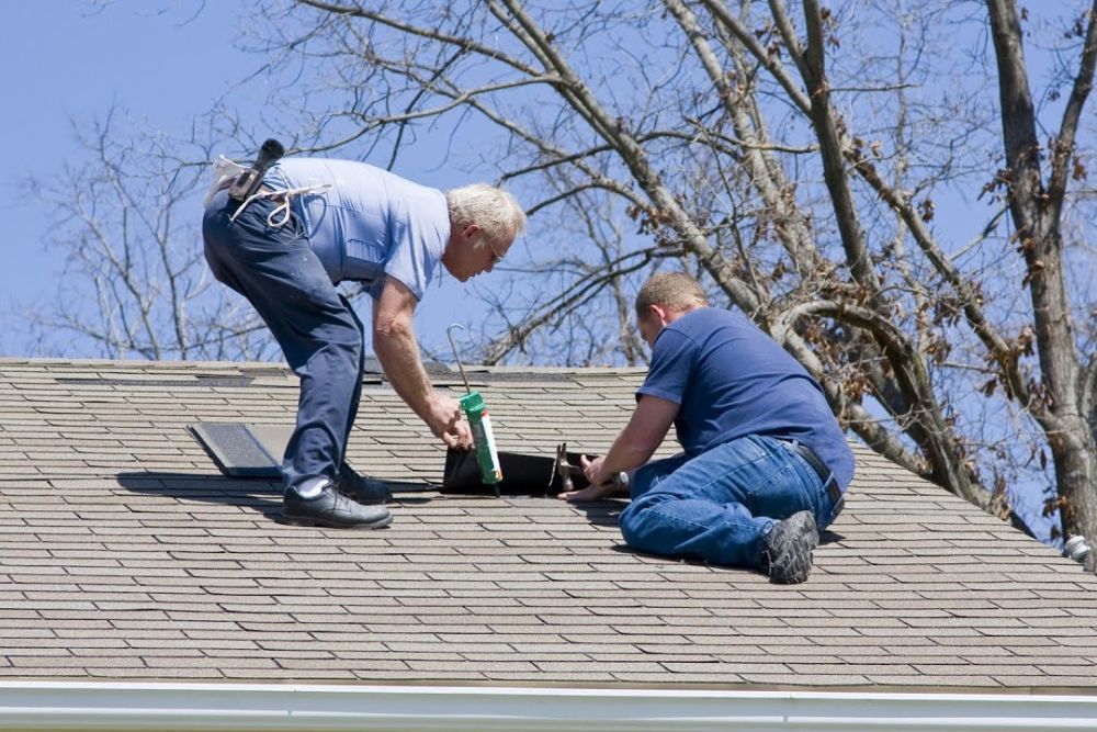 Two workers on a roof with a ladder, representing our emergency roofing service in Spokane, WA.