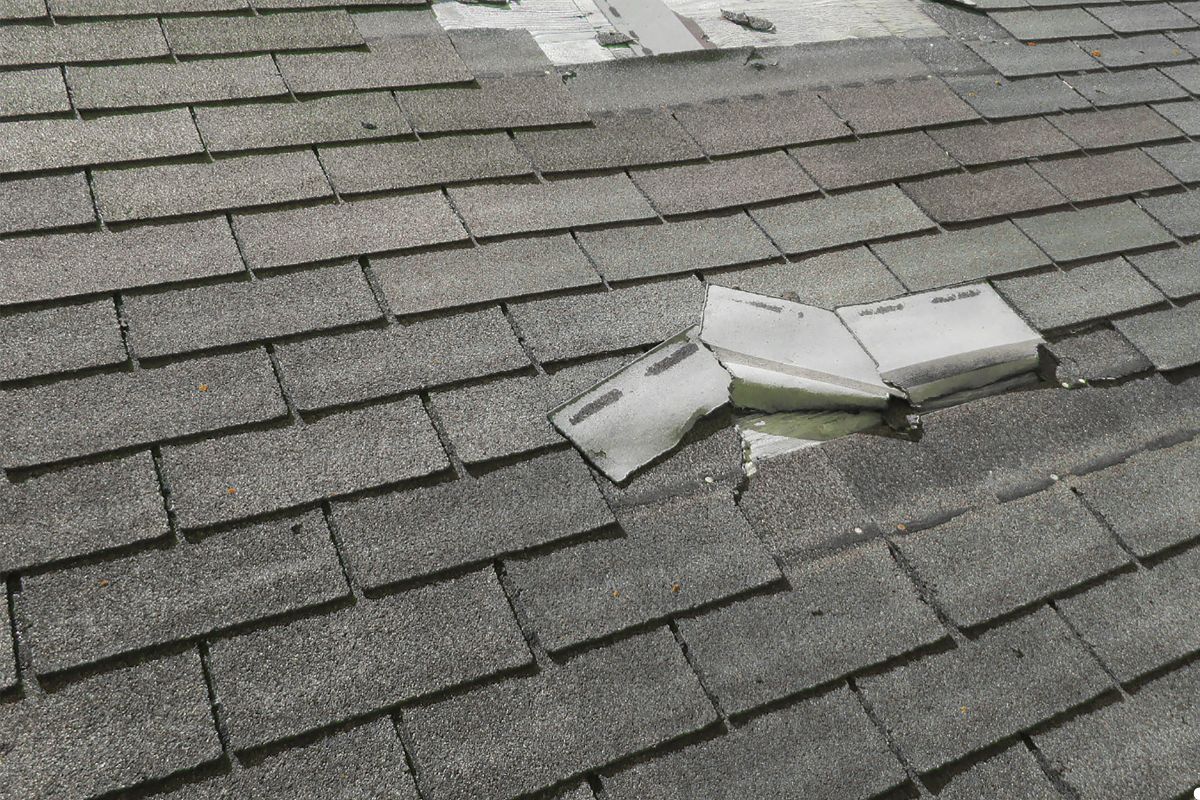 A roof featuring a broken shingle and a shattered window, indicating potential damage and disrepair.
