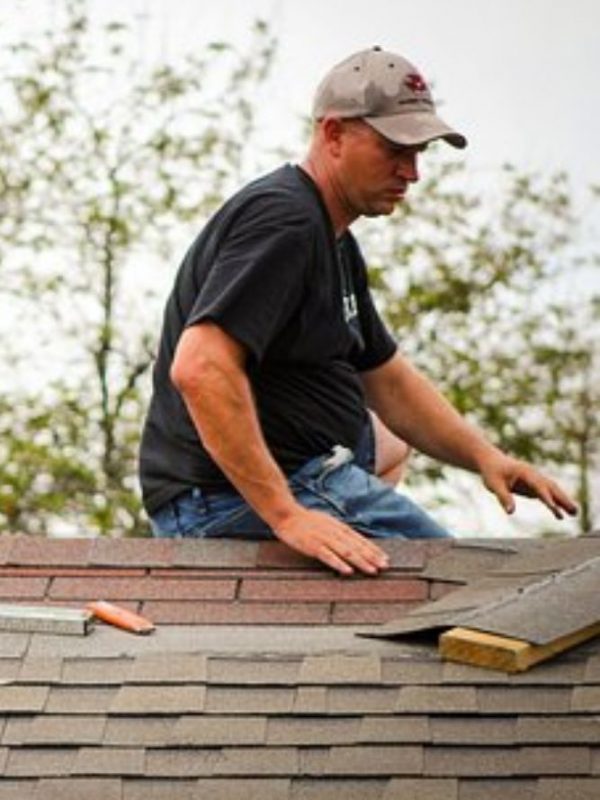 A man engaged in roofing work with a hammer, showcasing a construction service based in Spokane, WA.